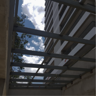 Cobertura metálica com terças de aço vista de baixo, integrada à fachada da edificação